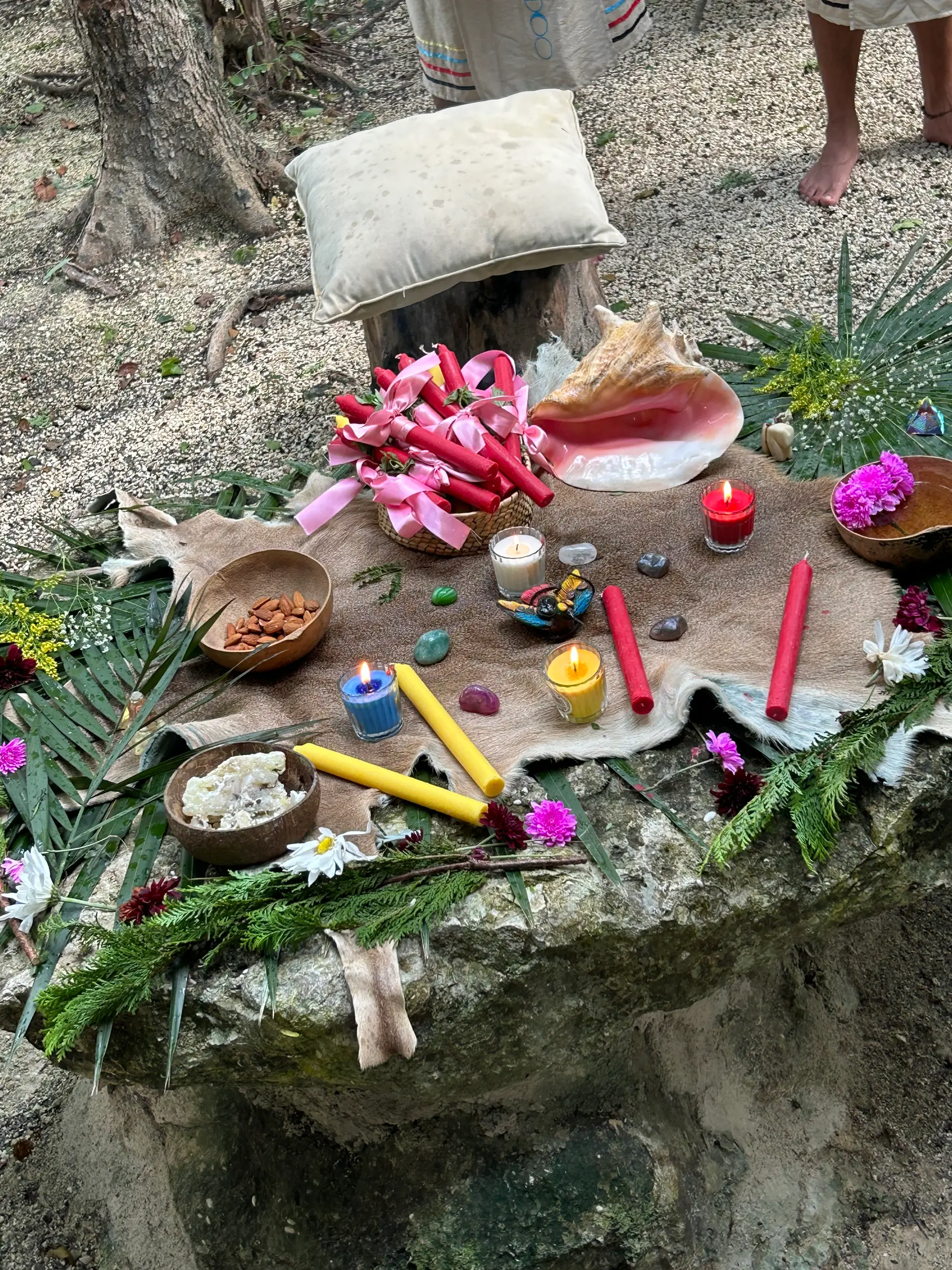 Altar con caracol, velas de colores, flores y piedras sobre la roca