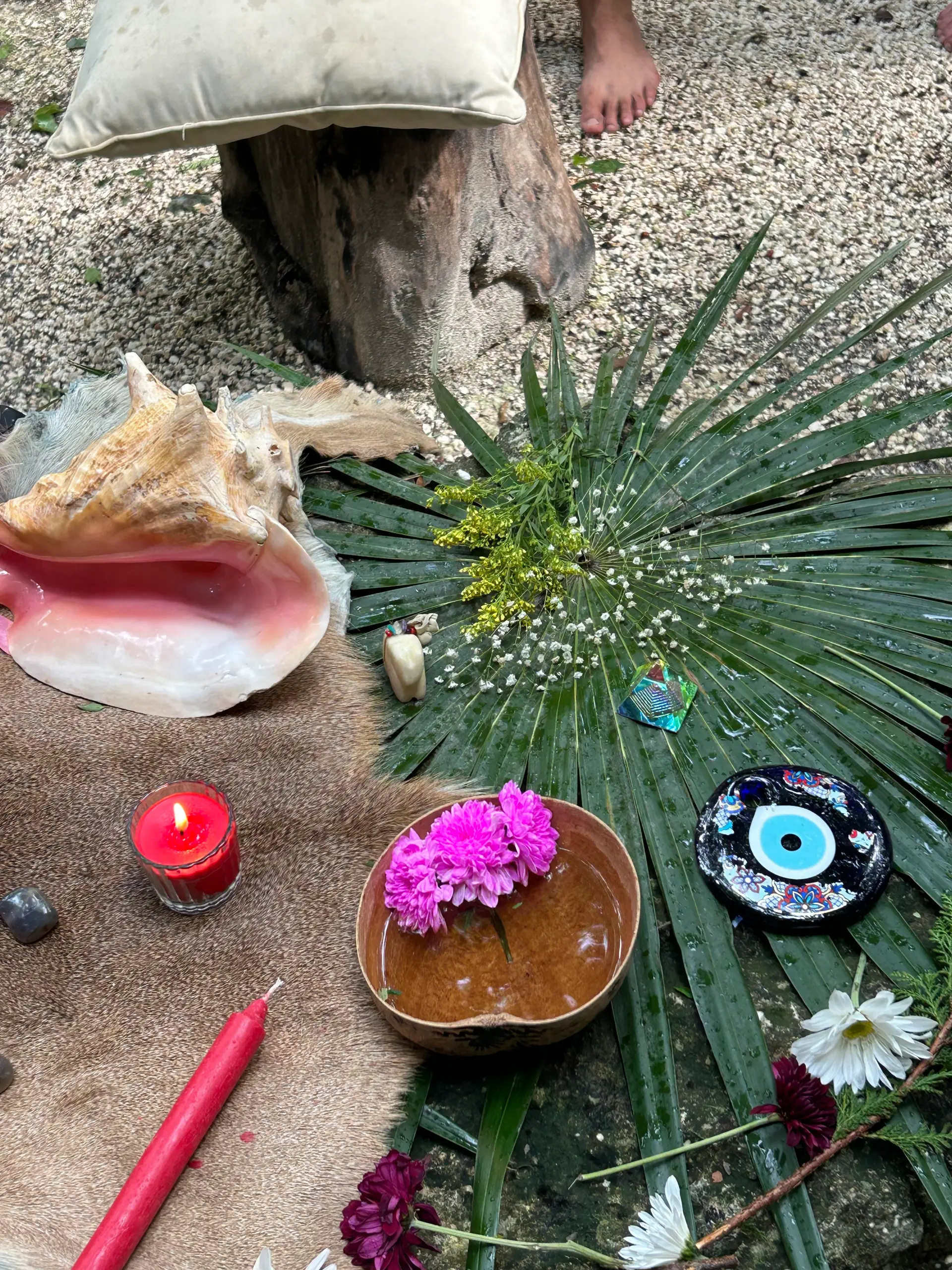 An altar with a conch, candles, flowers and palm leaves