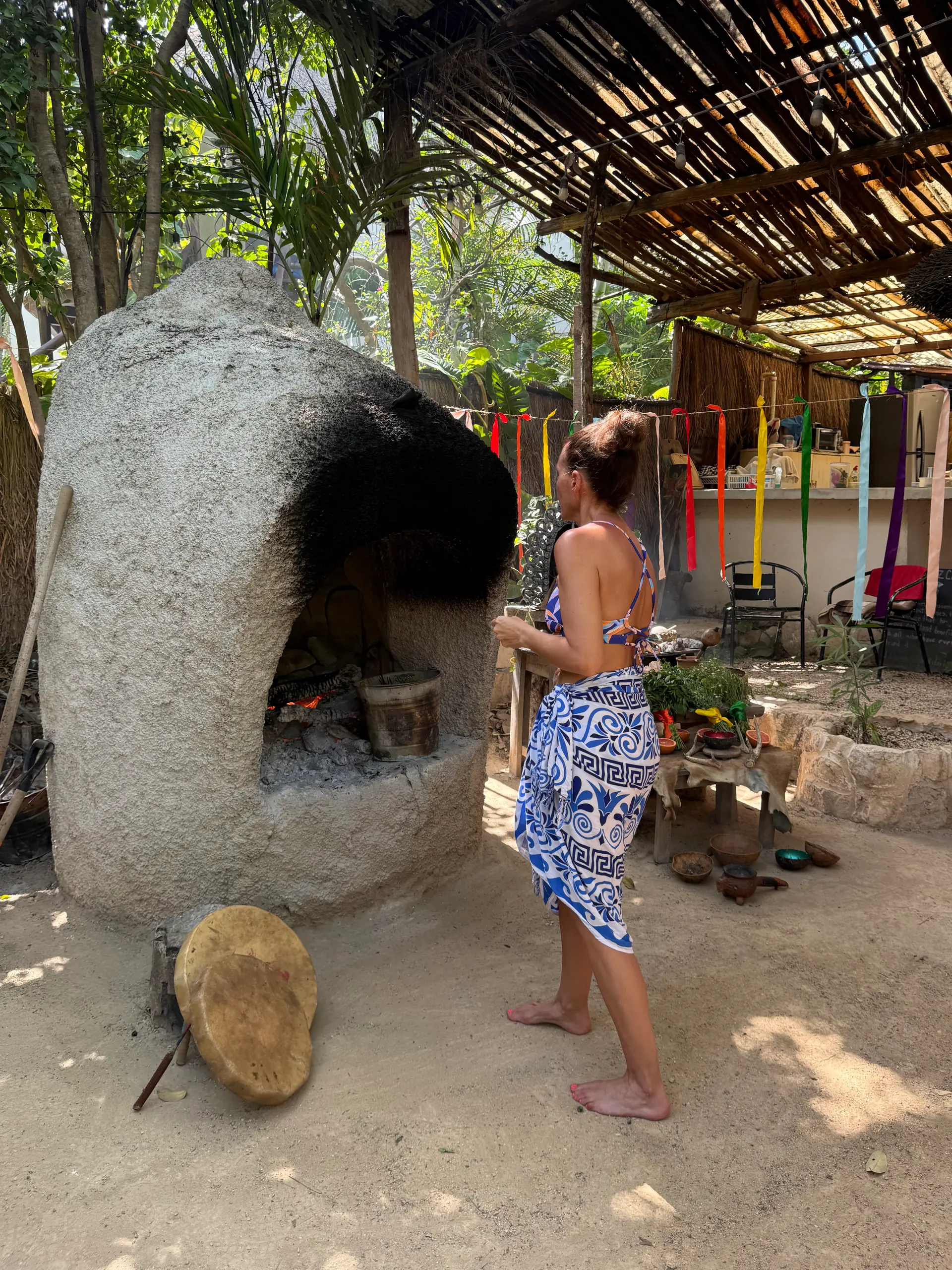 A lit stone oven, with the seven-chakra ribbons hanging beside it
